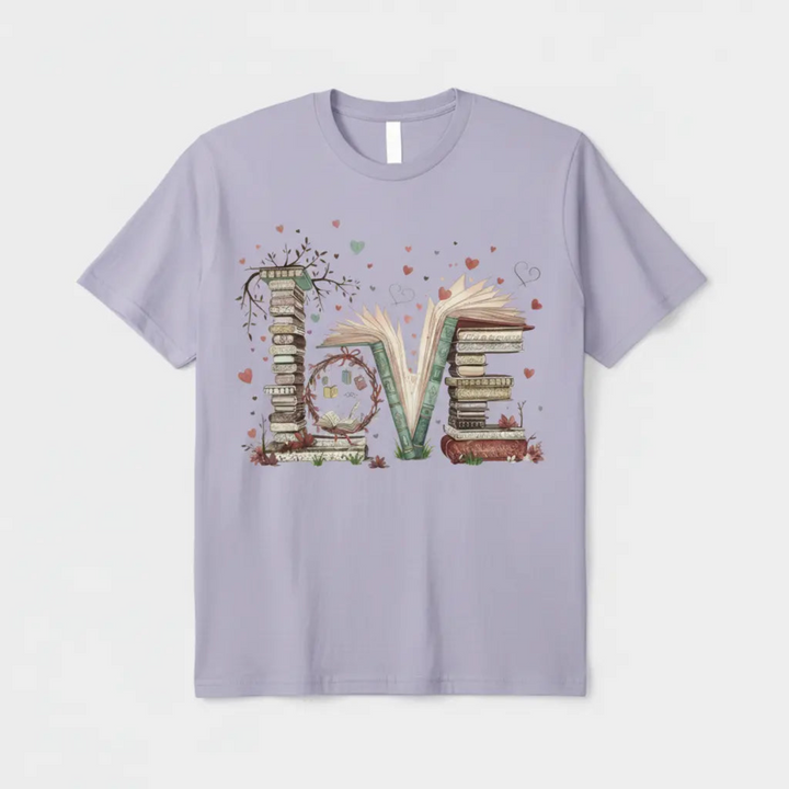 Charming Cute Bookworm Graphic Tee showcasing a detailed illustration of a cozy stack of literary books forming the word LOVE with floating hearts and delicate branches.